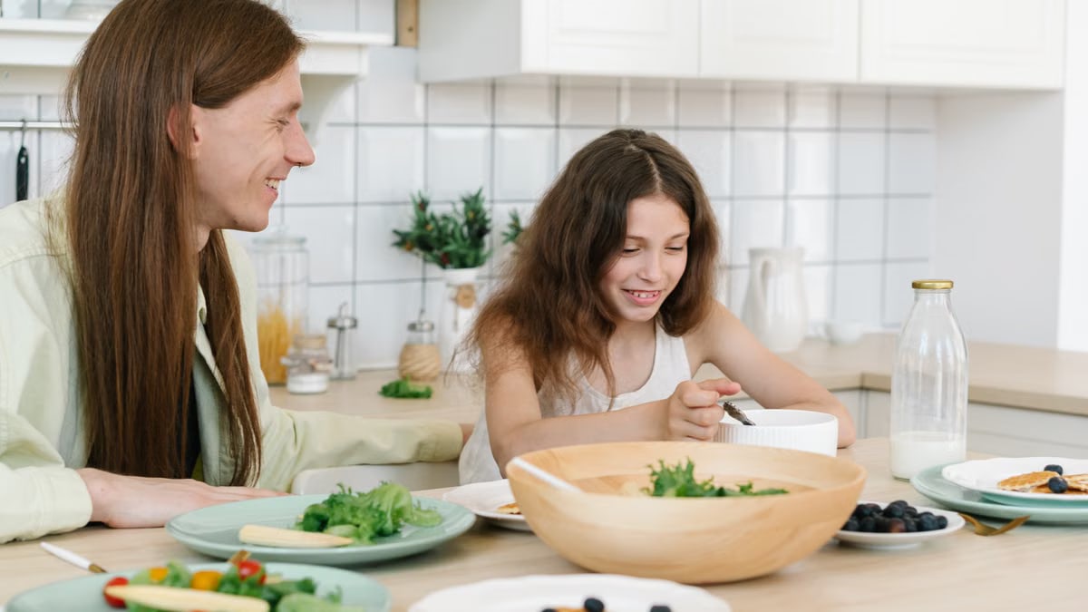 Father and daughter sharing a joyful breakfast at home in the kitchen.